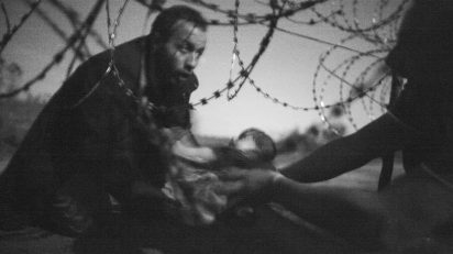 A man passes a baby through the fence at the Hungarian-Serbian border in Röszke, Hungary, 28 August 2015. © Warren Richardson, Australia.