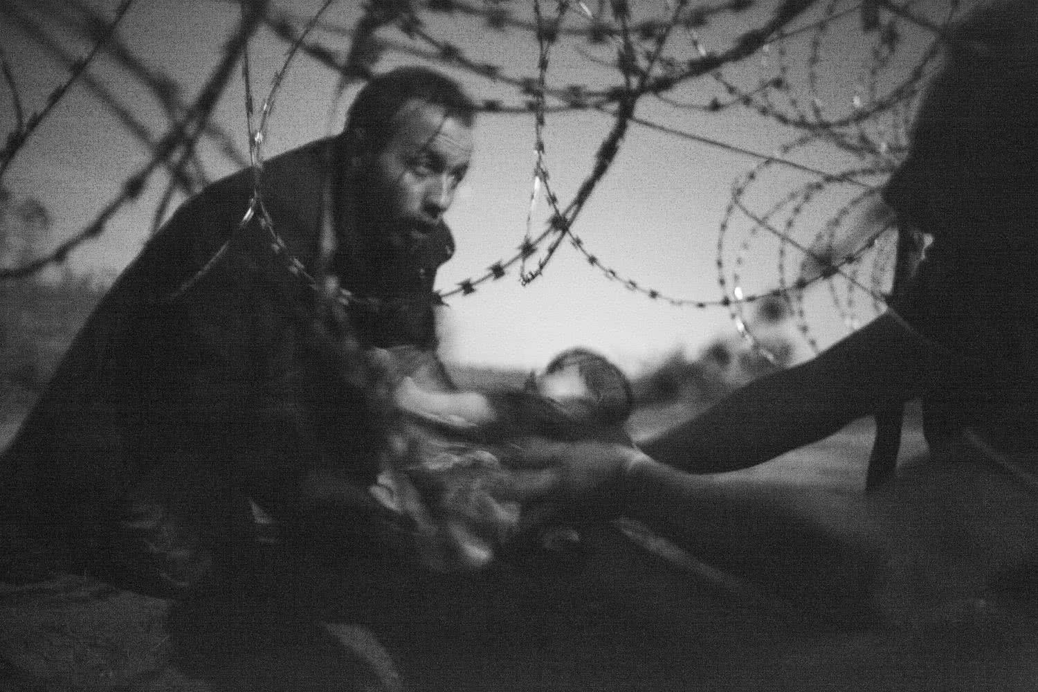 A man passes a baby through the fence at the Hungarian-Serbian border in Röszke, Hungary, 28 August 2015. © Warren Richardson, Australia.