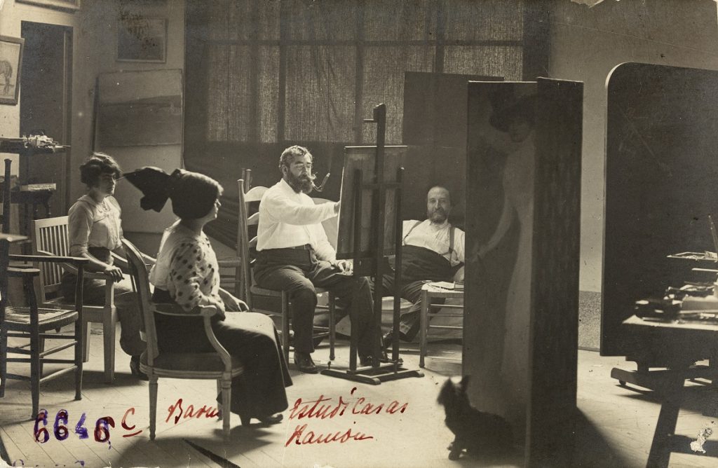 'Ramon Casas pintando a Júlia y a Flora Peraire en presencia de Adolf Mas'. Estudio de Fotografía A. Mas, 1912. © Fundació Institut Amatller d'Art Hispànic.